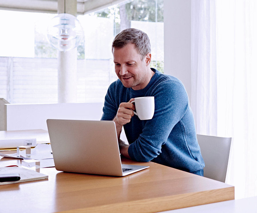 man drinking coffee looking at laptop