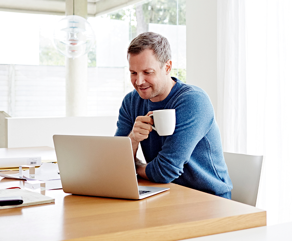 man drinking coffee looking at laptop